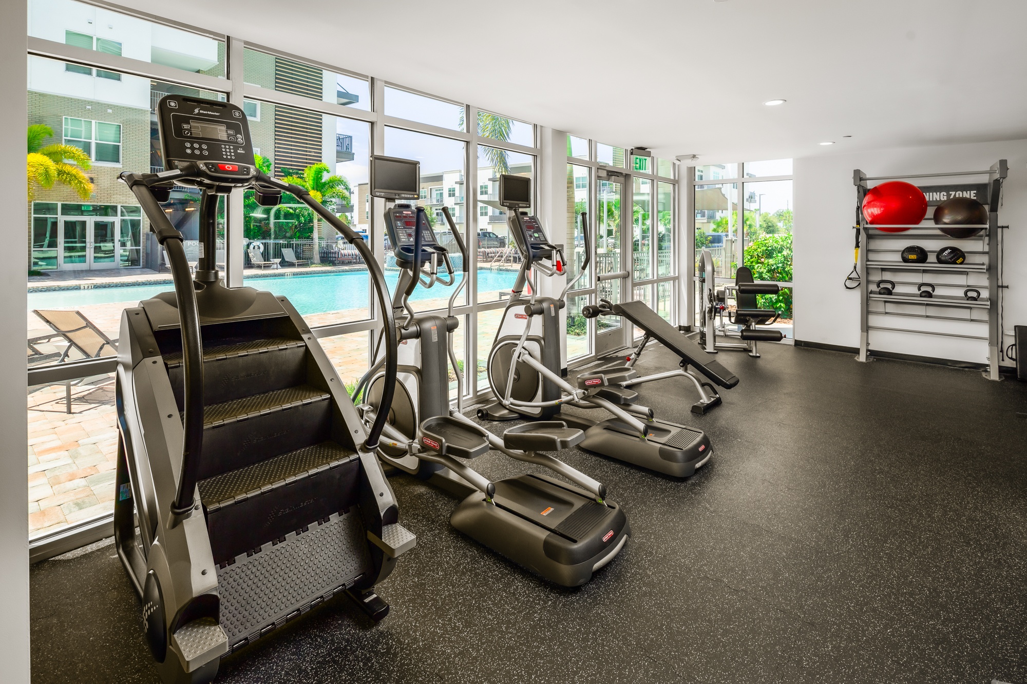 A gym with treadmills, elliptical machines, and a red ball.